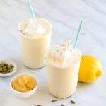 Two lemon milkshakes in glasses topped with whipped cream.