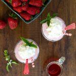 Overhead view of two Strawberry Milkshakes topped with whipped cream.
