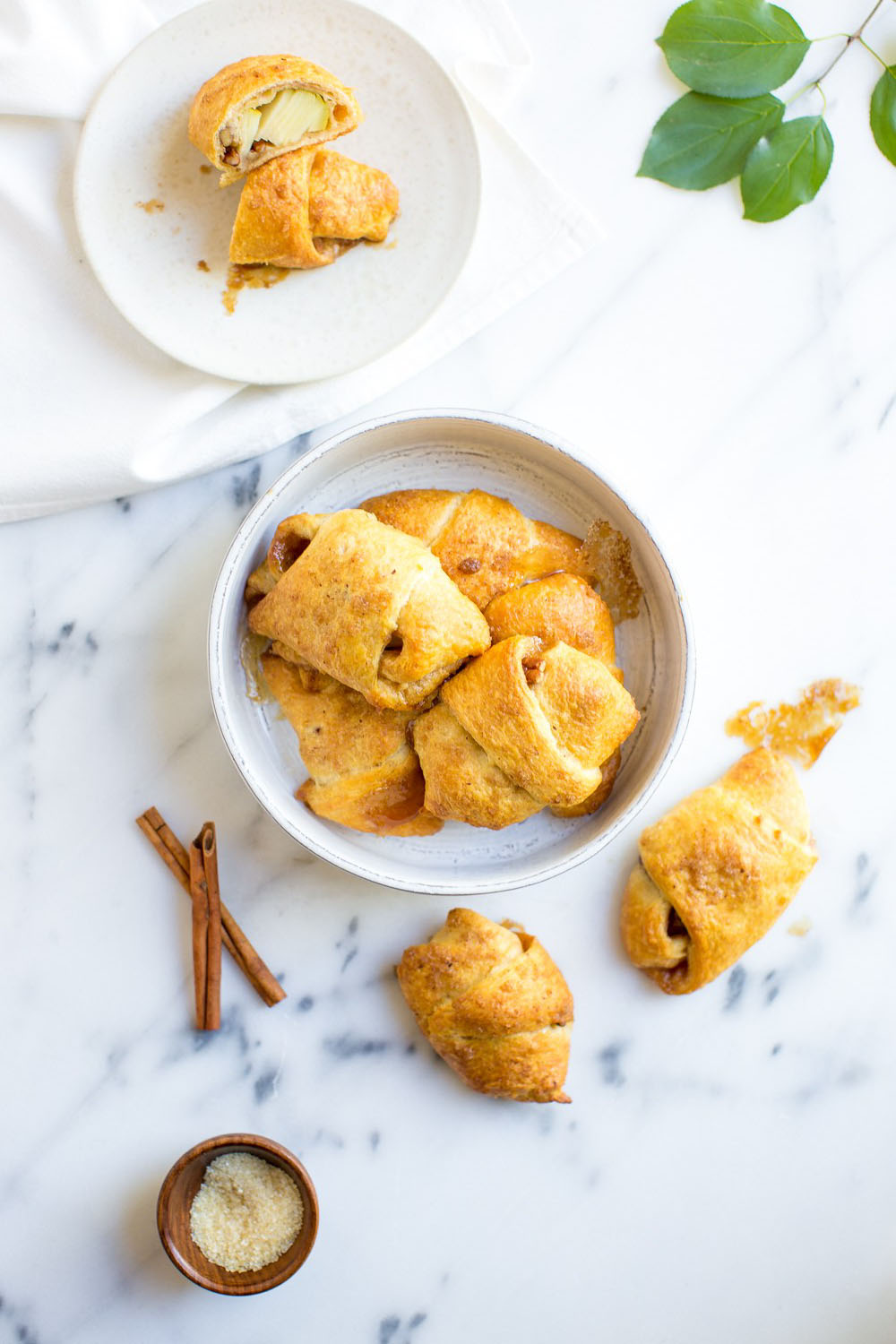 Crescent-wrapped apple cakes on a serving dish next to fresh cinnamon sticks.