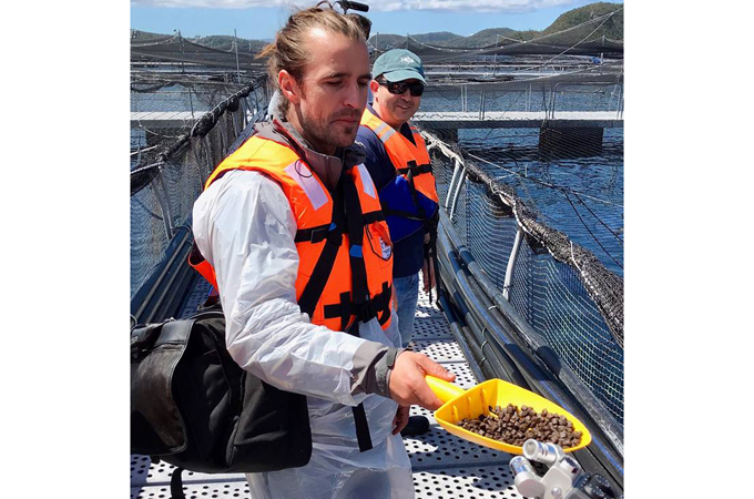Men on a fish farm with life vests holding fish feed.