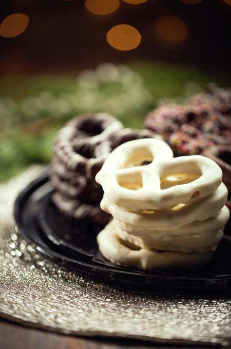 Black plate with white chocolate and chocolate covered pretzels.