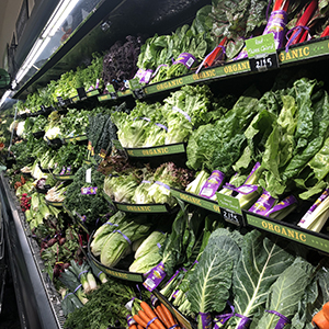 Produce department in a grocery store with a view of fresh, leafy vegetables.