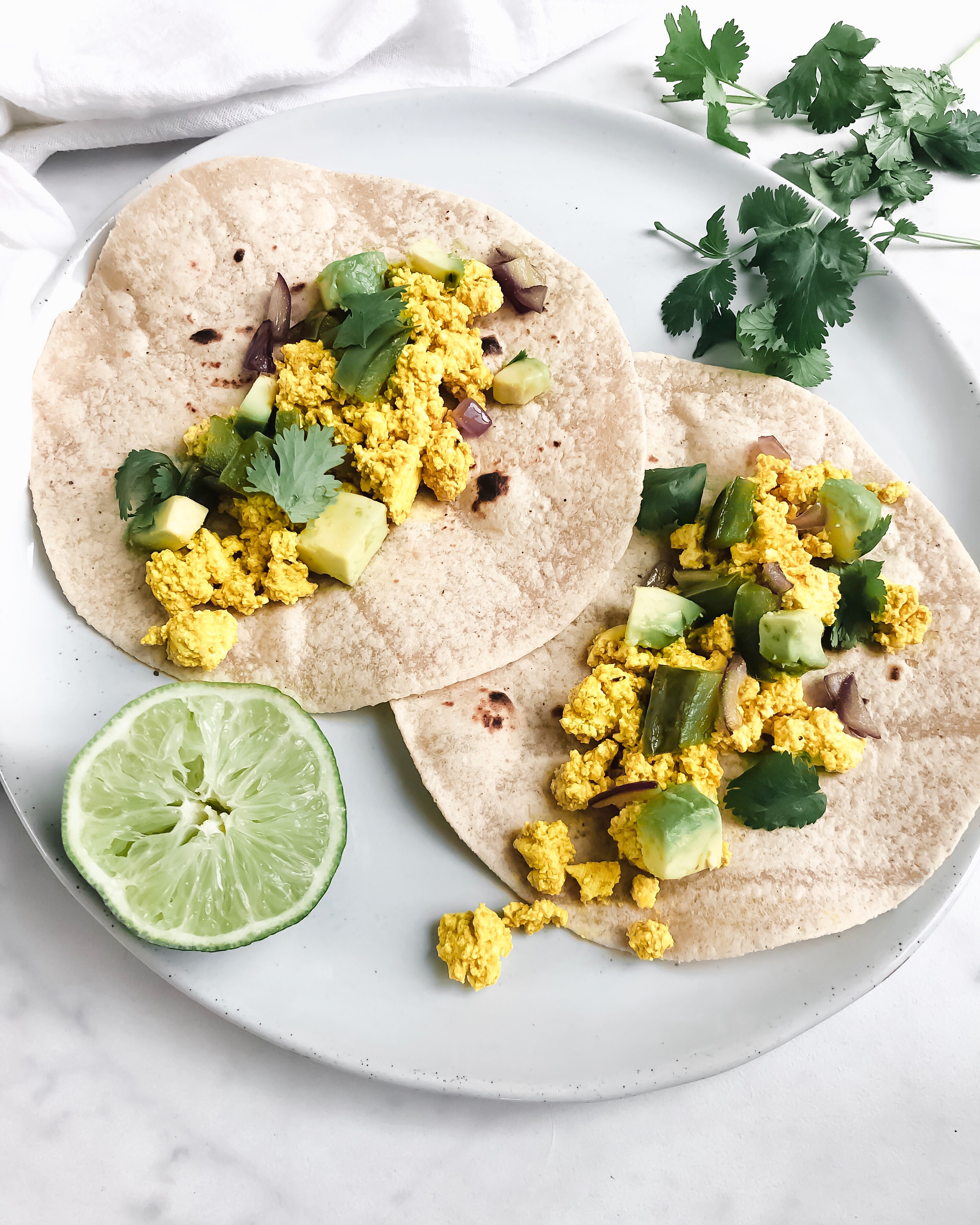 Crumbled Tofu Breakfast Tacos on a plate with lime and cilantro.