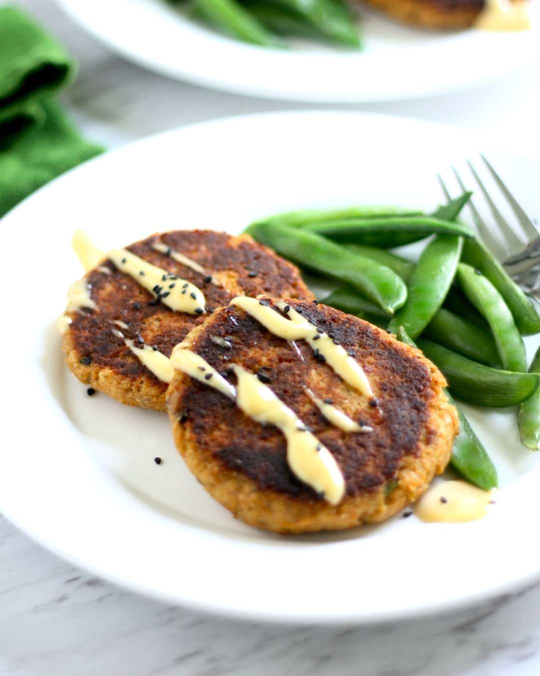 Asian Salmon Patties topped with aioli and served with cooked snap peas.
