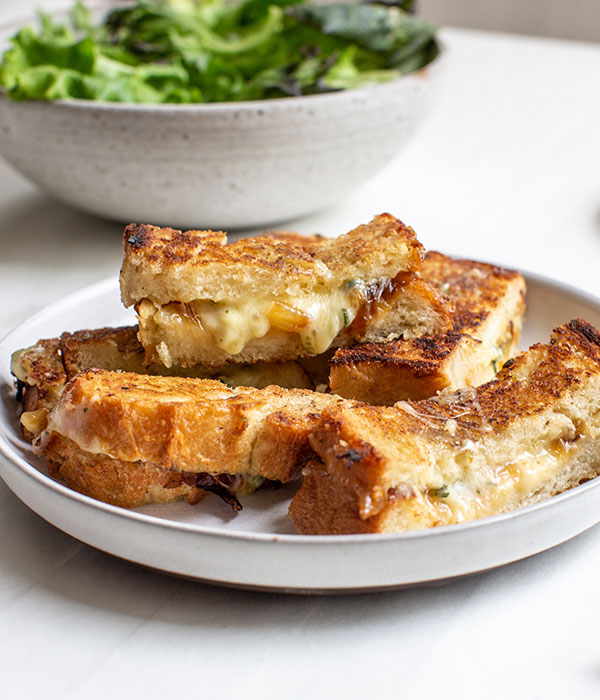 Grilled cheese cut into thin slices and served on a plate.