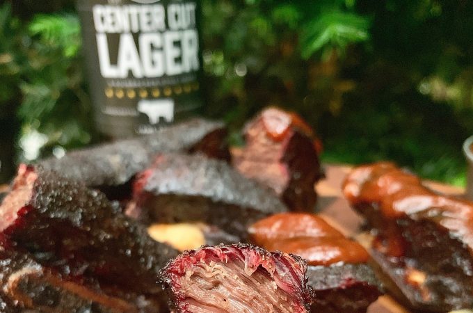 Charred meat on a cutting board with Center Cut Lager barbeque sauce.