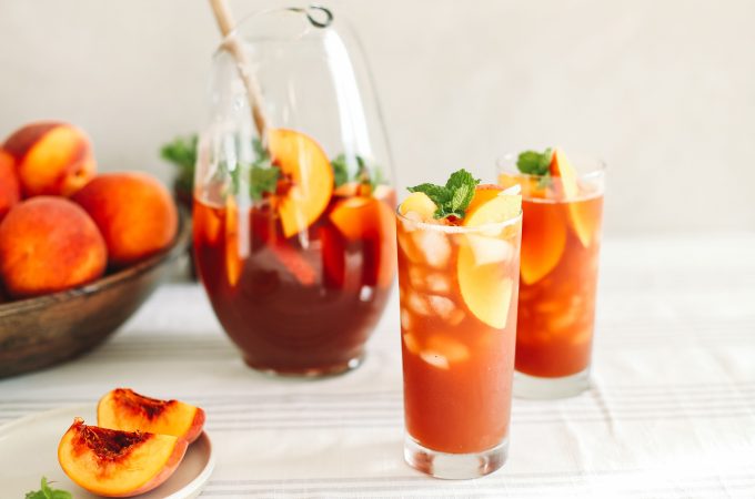 Fresh peach tea in glasses with ice and fresh peaches.