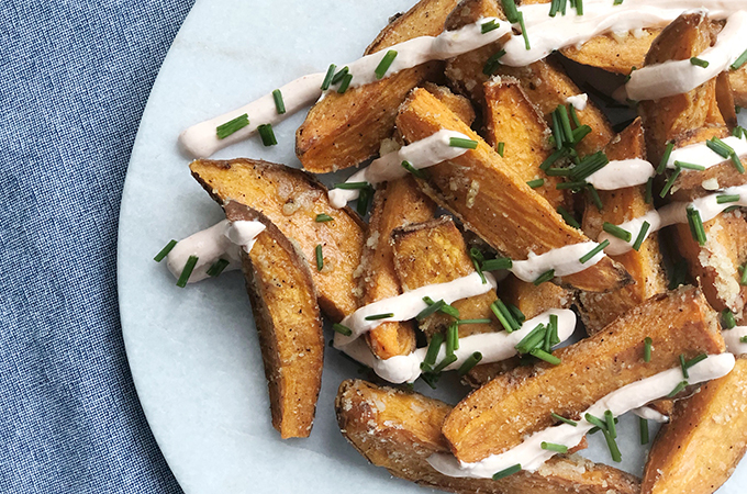 Plate of potatoes wedges drizzled with a white cream sauce.