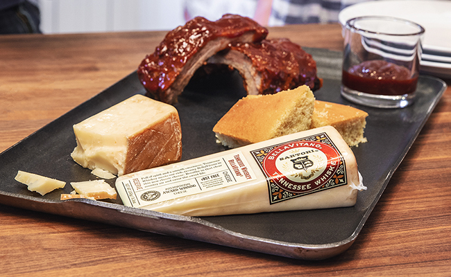 Serving platter with BBQ pork ribs, cornbread, and a Satori cheese wedge.