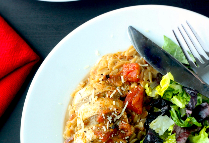 Sliced chicken breast served over rice with a side salad.