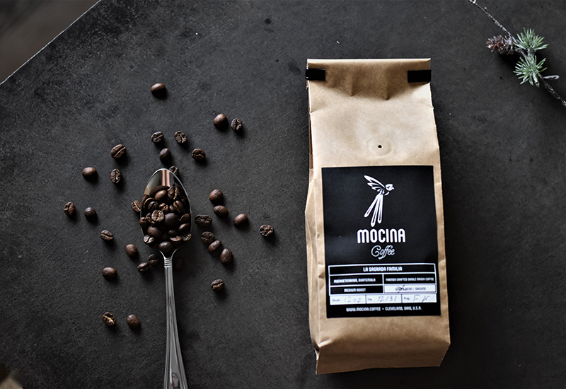 Bag of Mocina whole coffee beans next to a spoon with coffee beans.