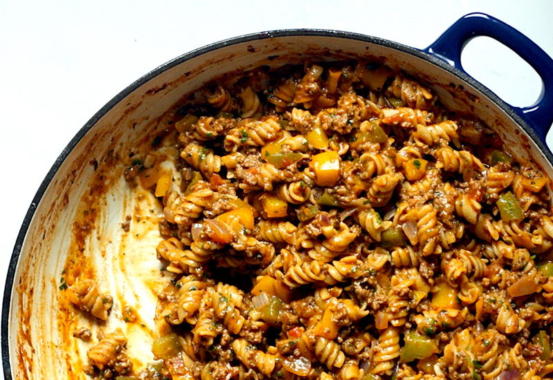 Rigatoni pasta with ground beef, bell peppers and a taco seasoning-based sauce in a blue cooking pot.