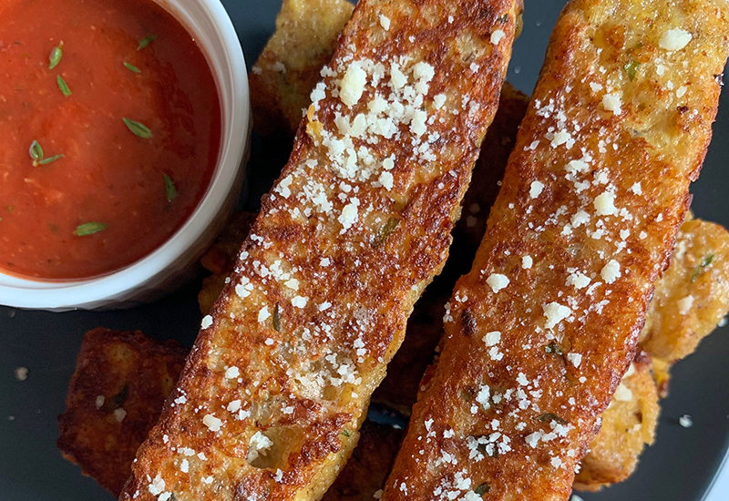 Savory parmesan crusted French toast next to a tomato dipping sauce.