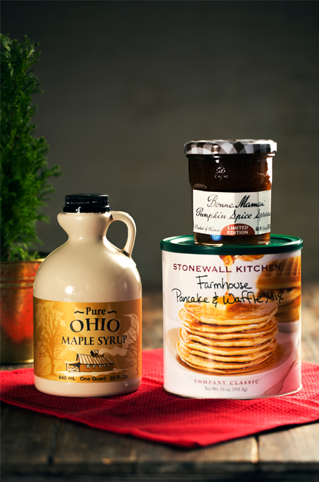 A container of pure maple syrup beside a farmhouse pancake and waffle mix and a jar of pumpkin spice spread.