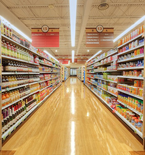 Brightly lit grocery store aisle with neatly stocked shelves of various food products.