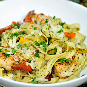 Fettuccini pasta with pesto, shrimp, parmesan cheese, and grilled vegetables.