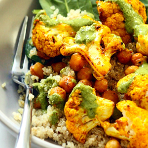 Bowl with grains, chickpeas, a green sauce and roasted seasoned cauliflower.