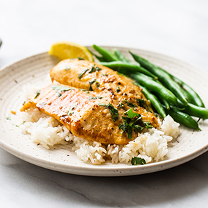 Plated with rice topped with seasoned tilapia and a side of green beans.