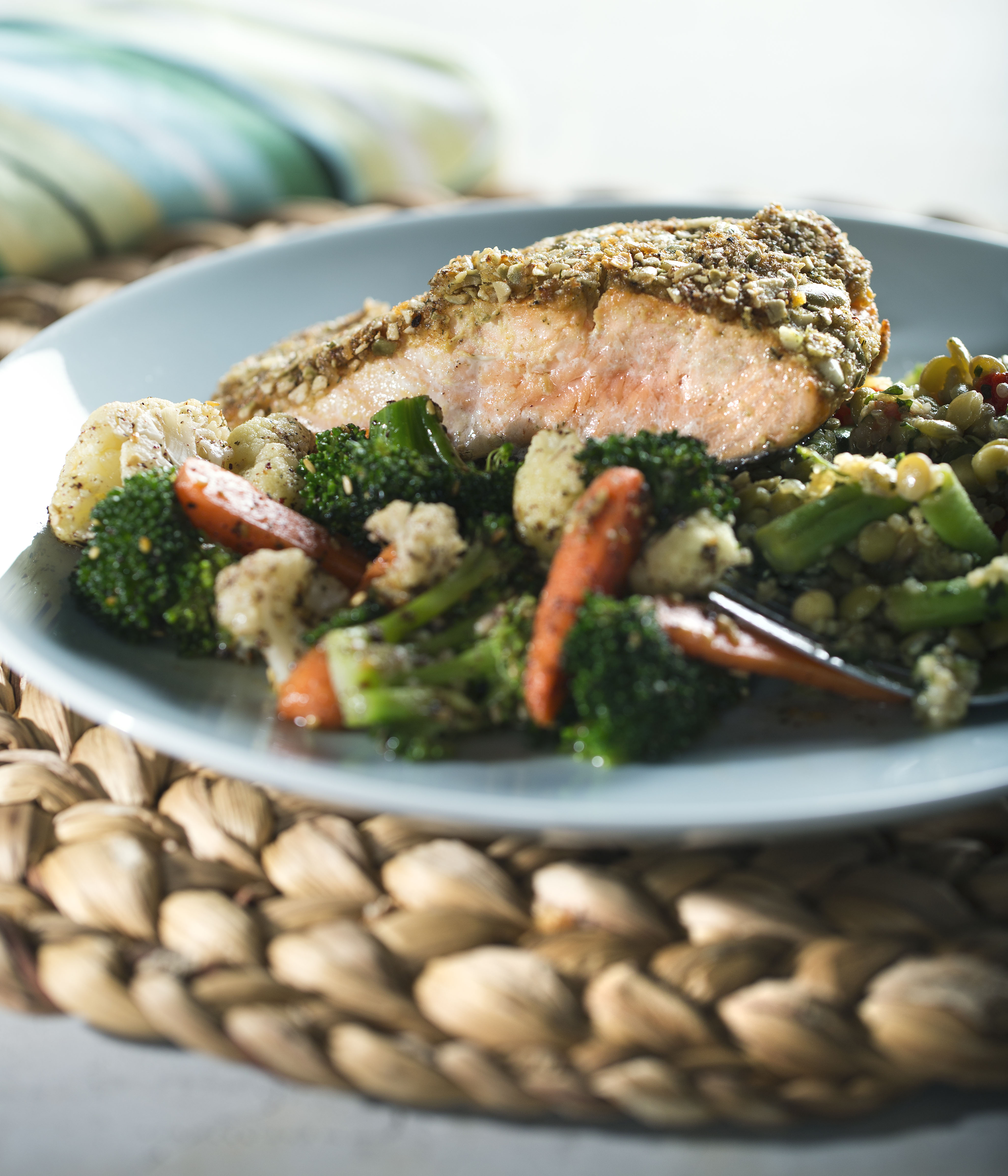 Pepita Crusted Salmon fillet served on a plate with broccoli, cauliflower, and carrots.