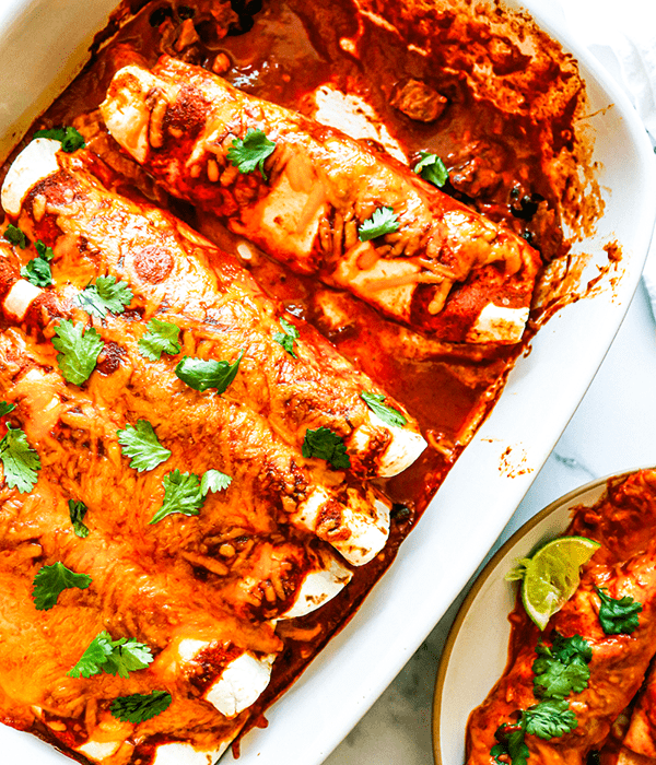 Vertical Images of Enchiladas in a Baking Dish with Sauce and Fresh Herbs