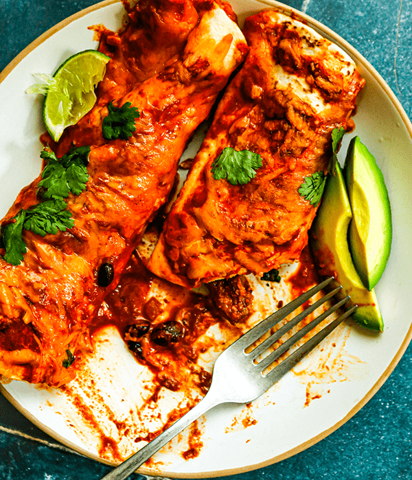Two Steak Enchiladas on a Plate with Fresh Avocado and Lime Slices