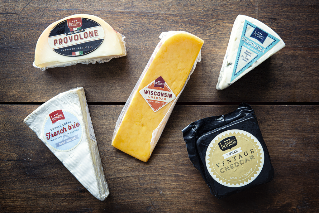 An assortment of Heinen's Hand-Selected Cheeses, including provolone, Wisconsin cheddar, French brie, gorgonzola, and vintage cheddar.