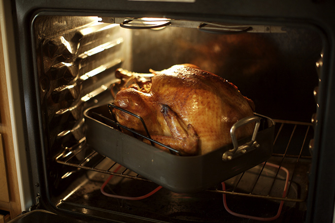 Oven with a whole turkey being cooked in a turkey roaster.