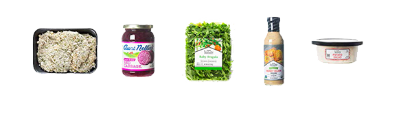 Spread of ingredients including packaged pork schnitzel, baby arugula, sweet and sour red cabbage, honey Dijon dressing and potato salad.