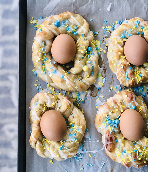 Circular Danishes drizzles with icing and sprinkles with a hardboiled egg in the middle.