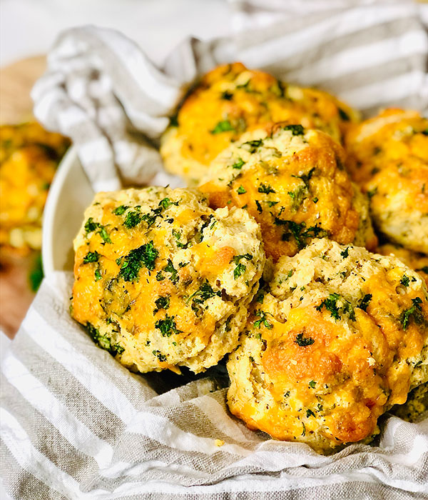 Basket with biscuits topped with cheddar and parsley.