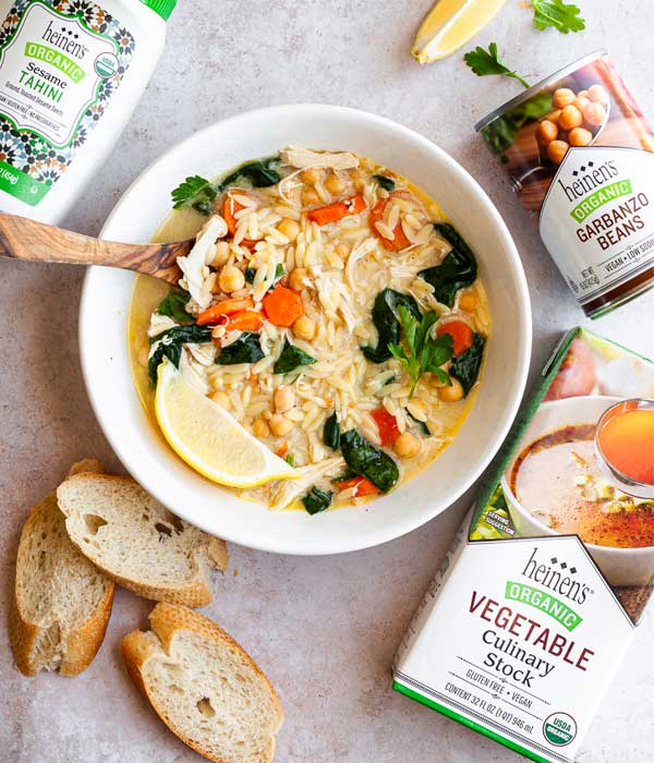 Lemon Chickpea Orzo Soup in a bowl with a side of Heinen's baguette.