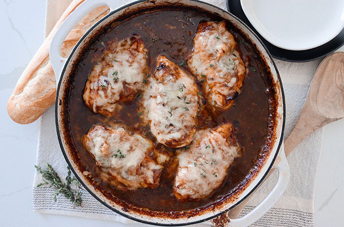 Pot with a French onion sauce and chicken breasts topped with Swiss cheese.