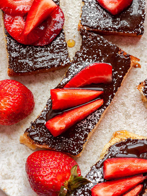 Crostini's topped with melted chocolate and sliced strawberries.
