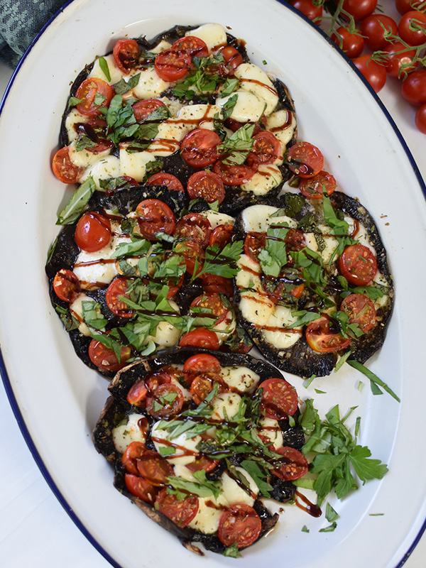 Caprese Stuffed Garlic Portobello Mushrooms on a serving dish, drizzled with balsamic glaze.