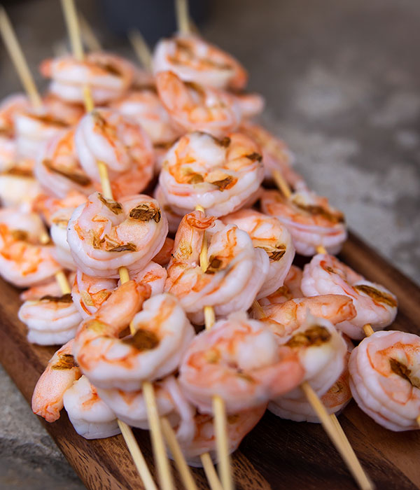 Cooked shrimp skewers stacked on a cutting board.