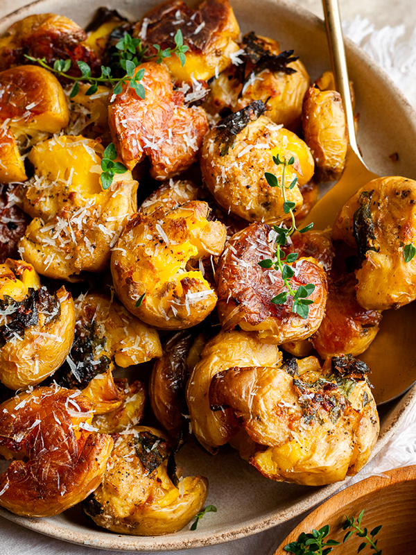 Garlic smashed potatoes in a serving bowl with a spoon.
