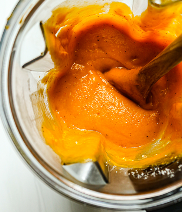 Roasted Butternut Squash Pasta Sauce in a blender with a wooden spoon.