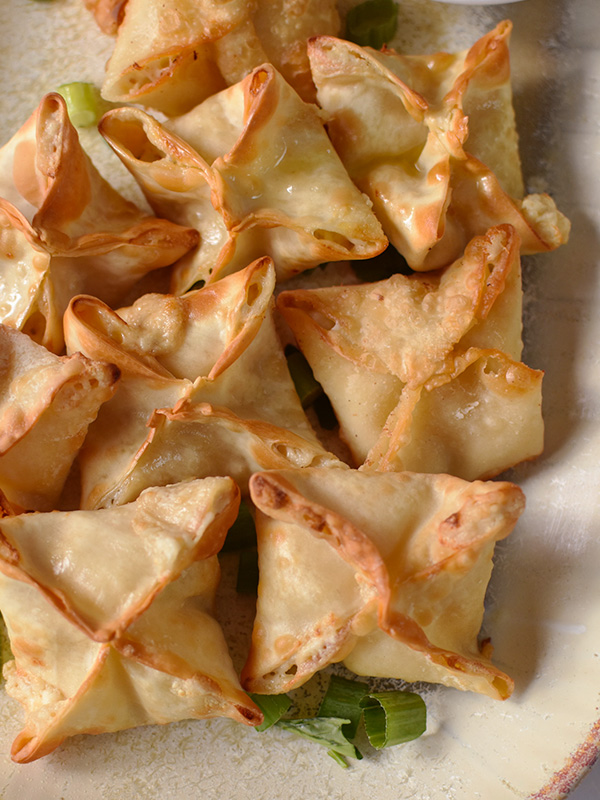 Crispy crab rangoons served on a plate.