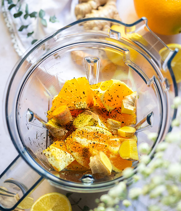 Chopped oranges, lemon, ginger and black pepper in a blender.
