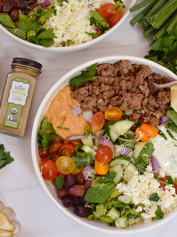 Bowl with lettuce, gyro meat, cucumbers, feta cheese, olives, and red onion.