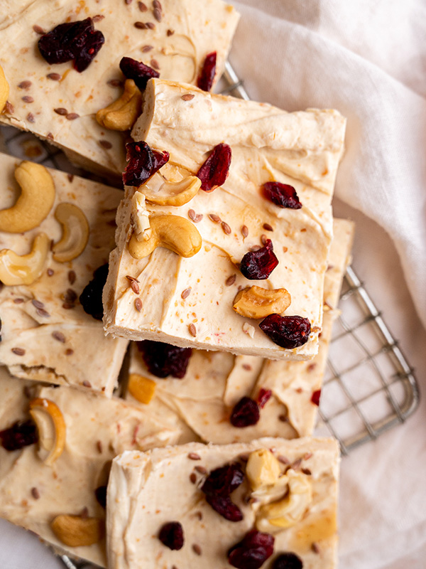 Healthy Peanut Butter Yogurt Bark cut into squares and topped with raisins and cashews.