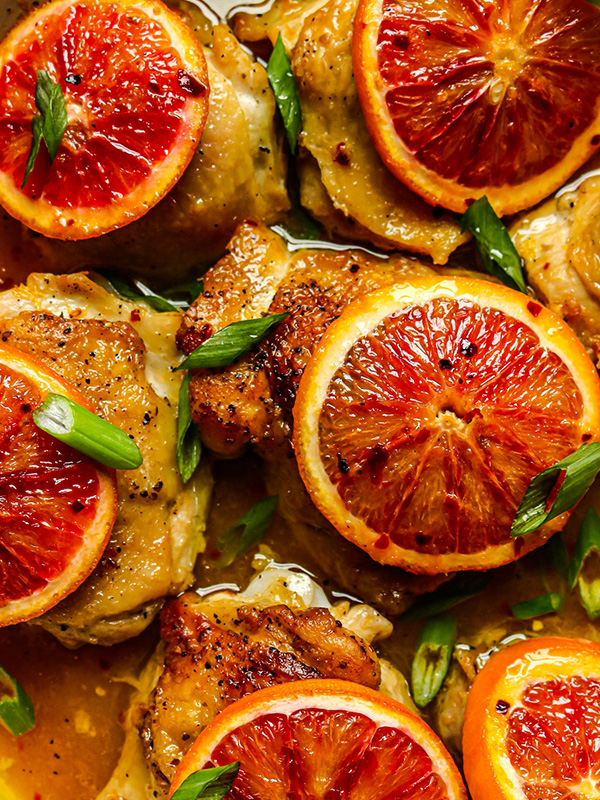 Chicken thighs topped with sliced blood oranges in a sauce.