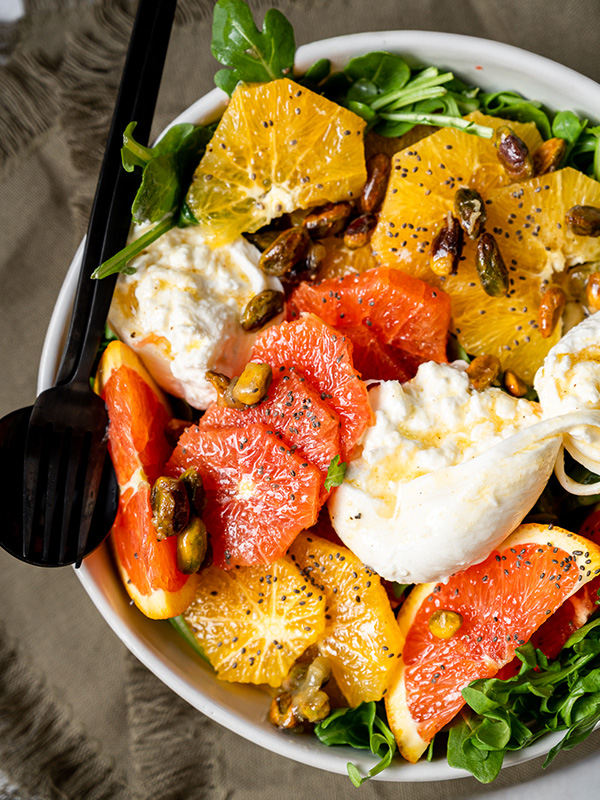 Citrus and burrata pistachio salad served in a bowl.