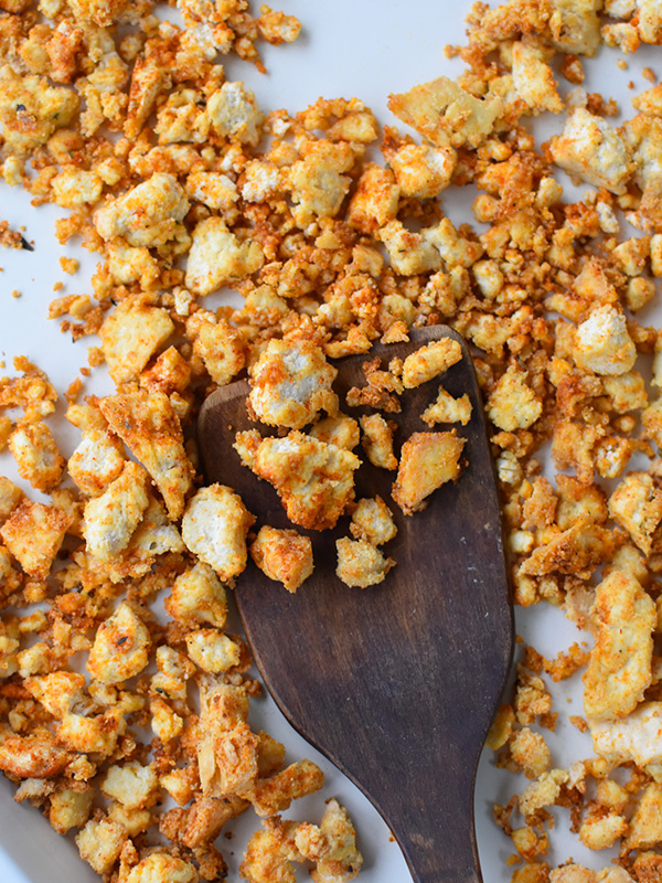 Crispy breaded tofu on a baking sheet with a spatula.