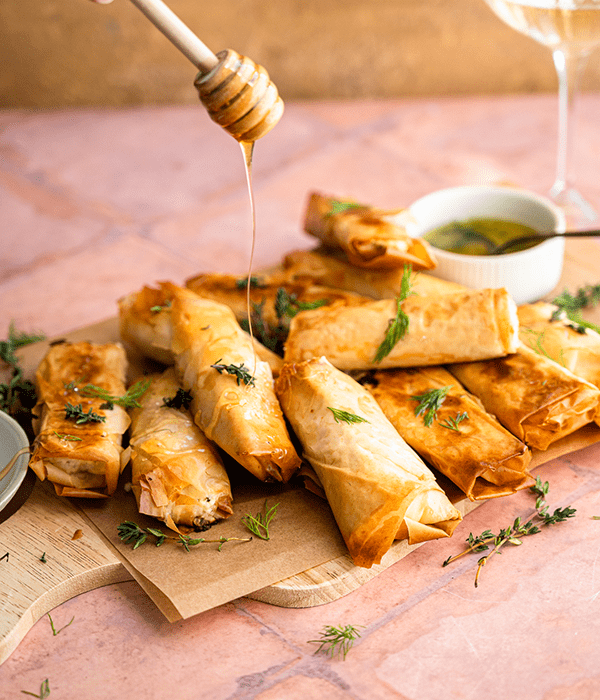 Oven Baked Feta Rolls Being Drizzled with Butter and Honey