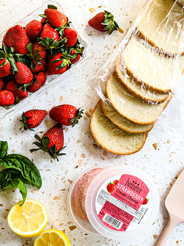 Counter with white bread, lemons, strawberries and strawberry cream cheese.