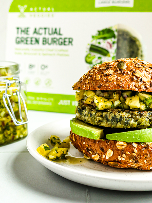 Green veggie burger on a multigrain bun with avocado and salsa.