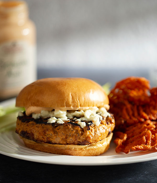Heinen's Buffalo Chicken Burger topped with Coleslaw on a Bun with a Side of Sweet Potato Fries