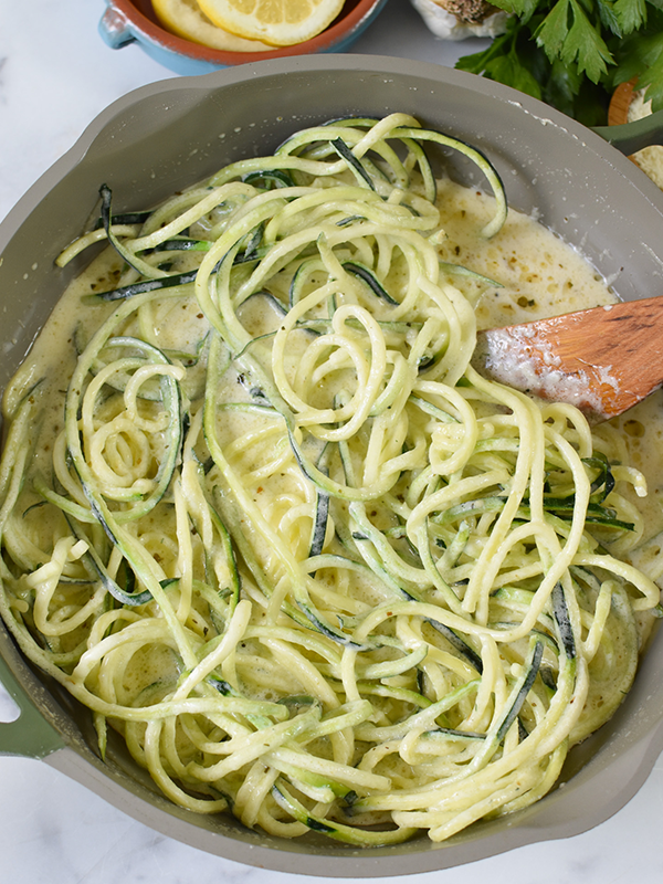 Zucchini noodles in a pan with a white cream sauce.