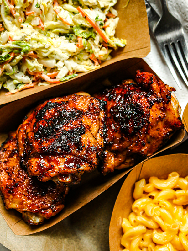 BBQ chicken thighs served with coleslaw and mac and cheese.